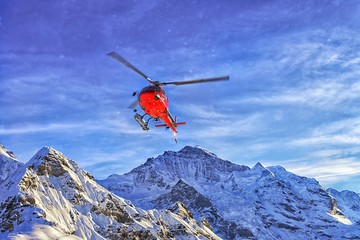 Red helicopter in the sky at swiss alps near in winter © Roman Babakin
