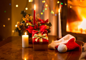 christmas photo of burning candles with giftbox against fireplac