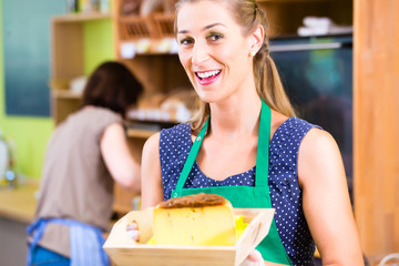 Verkäuferin an Käsetheke bietet Käse an