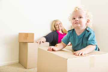 Fototapeta na wymiar Happy Mother and Son in Empty Room with Moving Boxes