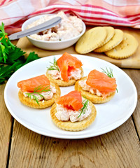 Fototapeta na wymiar Crackers with cream and salmon in plate on board