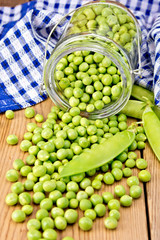Green peas in glass jar with cloth on board