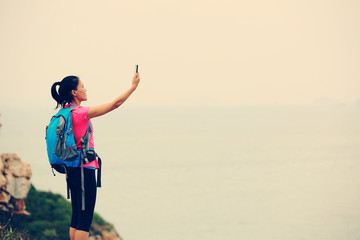 young woman hiker use smart phone taking photo at mountain peak