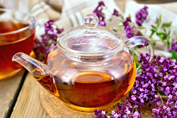 Tea of oregano in glass teapot on board with napkin