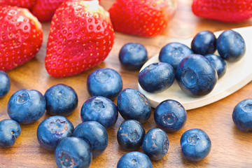 Fototapeta na wymiar Blueberries on wooden spoon with strawberries