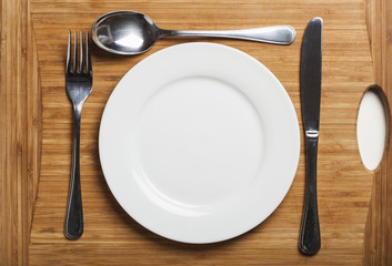 Stainless steel cutlery and plate on wooden board