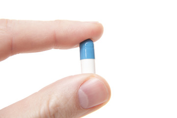 Hand holding single pill. All on white background.