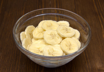Banana slices in glass bowl on wooden table