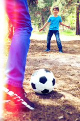 Happy dad and son playing football in the park
