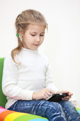 Child playing game on the cellphone, sitting indoor