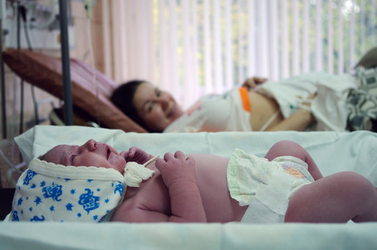 Newborn baby at desk next to her mother in maternity hospital