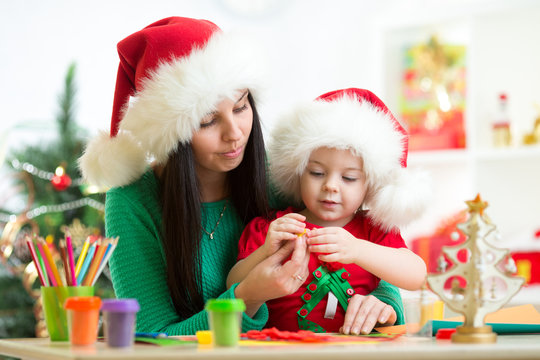 mother and kid daughter in Santa hats making christmas tree of