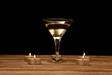 glass of martini with candles on a wooden table