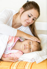 mother holding hand on sleeping daughter with care