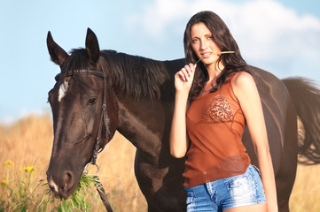 Obraz premium Young beautiful girl with a horse on field
