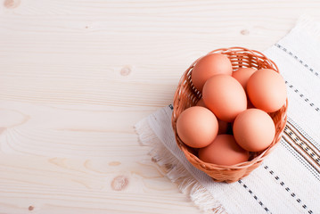 brown eggs in a wicker basket on a light wooden table top view