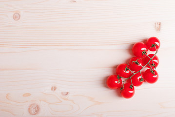 Naklejka na ściany i meble branch of cherry tomatoes on a light wooden table top view on th