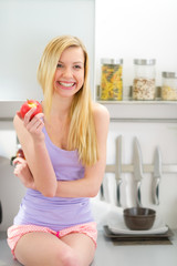 Young woman eating apple in kitchen