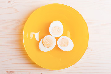 boiled eggs cut in half on white yellow on a light wooden table