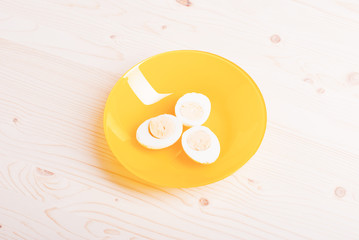 boiled eggs cut in half on white yellow on a light wooden table