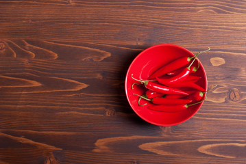 red chili peppers in the plate on a dark wooden table top view o