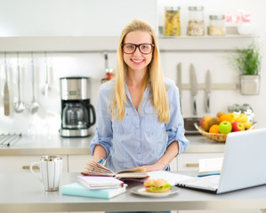 Obraz na płótnie Canvas Portrait of happy young woman studying in kitchen