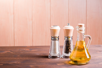 Obraz na płótnie Canvas salt and pepper and sunflower oil on brown desk side view