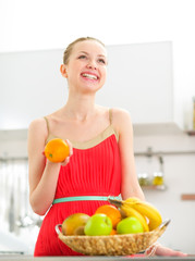 Happy young woman with fruits in kitchen