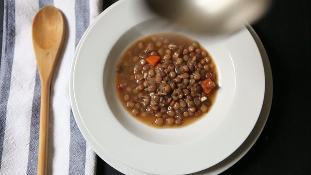 serving lentil soup on bowl