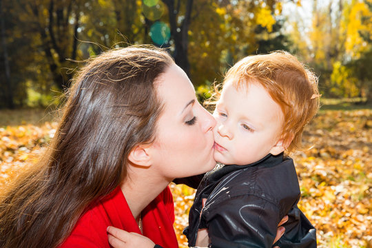 Happy mom and child boy hugging on nature at fall.