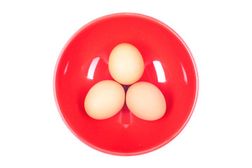Three brown eggs in red plate on white isolated background top v