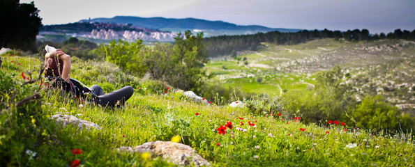 Woman lying in grass field panorama. City on background. 