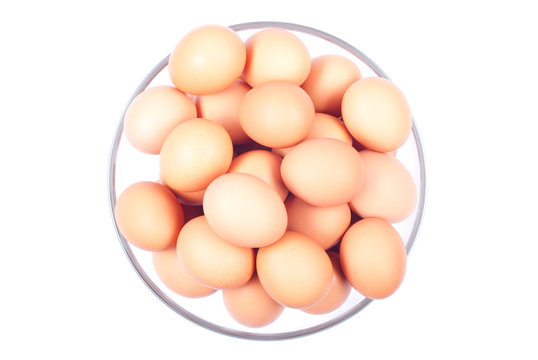 a lot of brown eggs in a large glass bowl isolated on white back