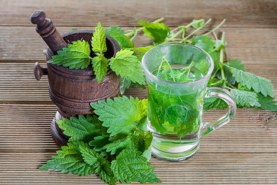 Tea with fresh nettles on a wooden background