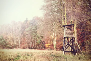 Rolgordijnen Retro filtered photo of a hunting pulpit on the edge of forest and field © MaciejBledowski