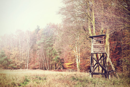 Retro filtered photo of a hunting pulpit on the edge of forest and field