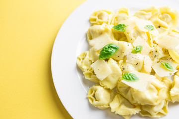 Italian tortellini dish on yellow background close-up