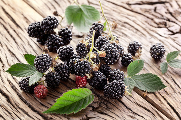 Blackberries with leaves on a old wooden table.