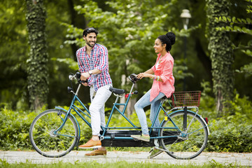 Young couple riding on the tandem bicycle