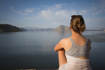 Young woman sitting next lake. 