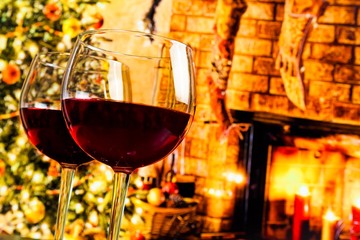 detail of two red wine glasses against christmas tree background