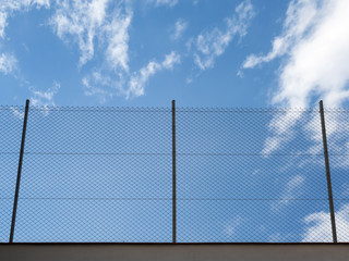 Metal Rabitz mesh fence against blue sky