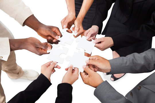 Business People's Hands Solving Jigsaw Puzzle
