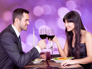 Happy Young Couple Toasting Wineglasses At Restaurant Table