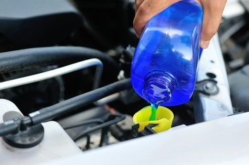 hand adding auto glass cleaner for car 