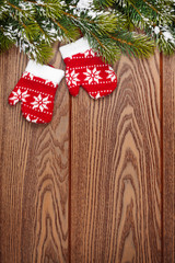 Christmas mitten decor and snow fir tree over wooden background