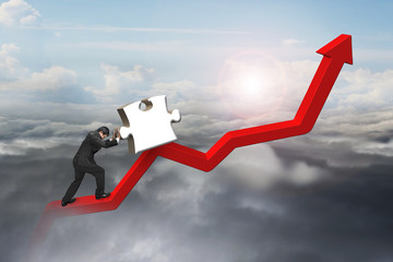 businessman pushing 3D jigsaw puzzle upward on red trend line