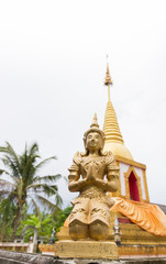 Fototapeta premium praying angel statue beside the buddhist pagoda
