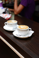 Cups of coffee with cute drawing in cafe