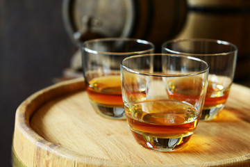 Glasses of brandy in cellar with old barrels